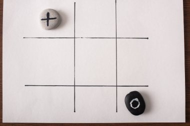 Tic tac toe oyununun üst görünümü üzerinde hiçbir şey olmayan taşlar ve beyaz yüzey üzerinde çapraz