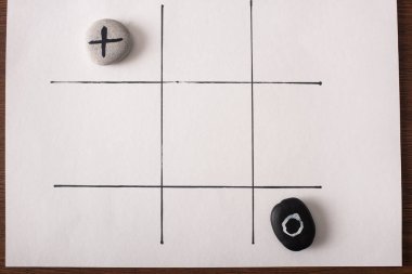 top view of tic tac toe game with stones marked with naught and cross on white surface clipart