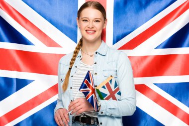 smiling pretty girl with braid holding book on uk flag background