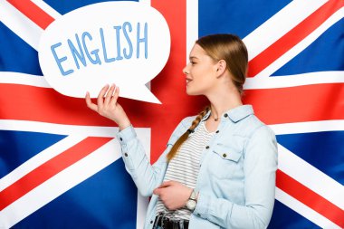 smiling pretty girl with braid holding speech bubble with English lettering on uk flag background clipart