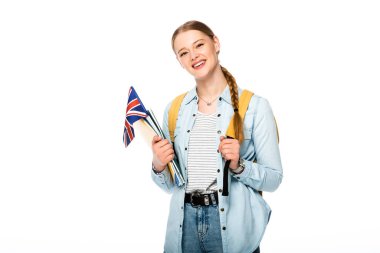 Örgülü ve sırt çantalı gülümseyen kız Birleşik Krallık bayrağı ve beyaz üzerine izole edilmiş defterler taşıyor.