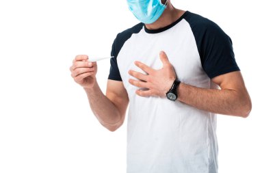 Tıbbi maskeli, dijital termometreyi beyaz üzerinde tutan hasta adam görüntüsü. 