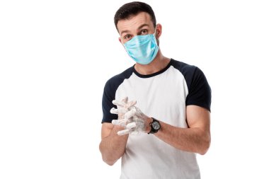 Tıbbi maskeli bir adam beyazların üzerinde ellerini yıkıyor. 