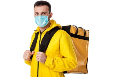 Mavi tıbbi maskeli ve sırt çantalı teslimatçı beyaz üzerine izole edilmiş. 