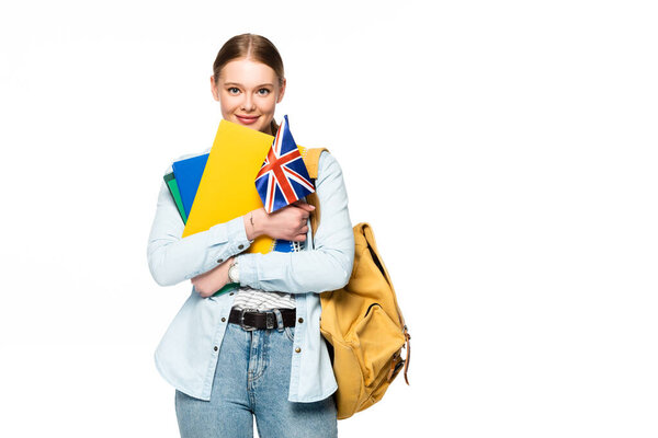 smiling girl with backpack holding copybooks and uk flag isolated on white