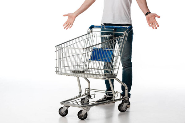 cropped view of man gesturing while standing near empty shopping cart on white 