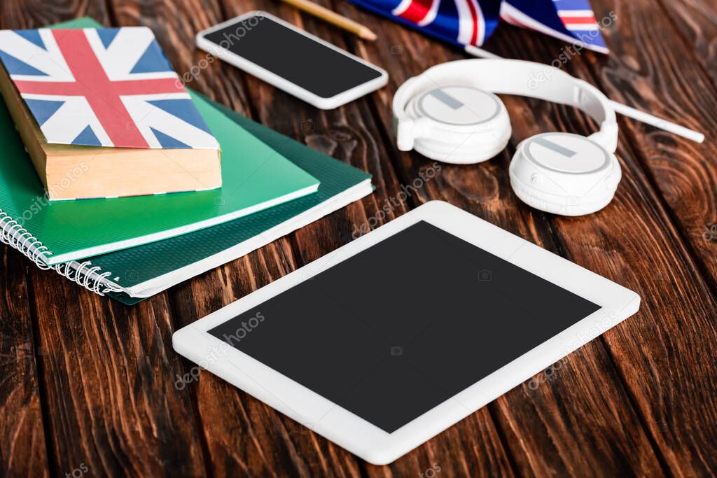 gadgets near copybooks and book with uk flag on wooden table