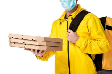 Medikal maskeli teslimatçının beyaz üzerinde izole edilmiş karton pizza kutuları taşıdığı görüntüler. 