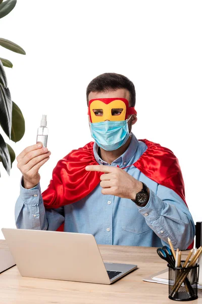 头戴医疗面罩 头戴超级英雄斗篷的男子 手拿着手指 在笔记本电脑旁边用卫生纸擦拭 白色隔离 — 图库照片