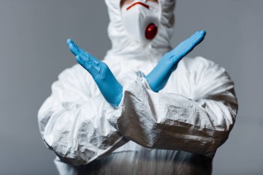 cropped view of mature doctor in hazmat suit, medical mask and latex gloves standing with crossed arms isolated on grey  clipart