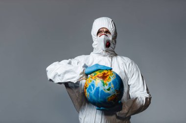 man in personal protective equipment holding globe isolated on grey  clipart