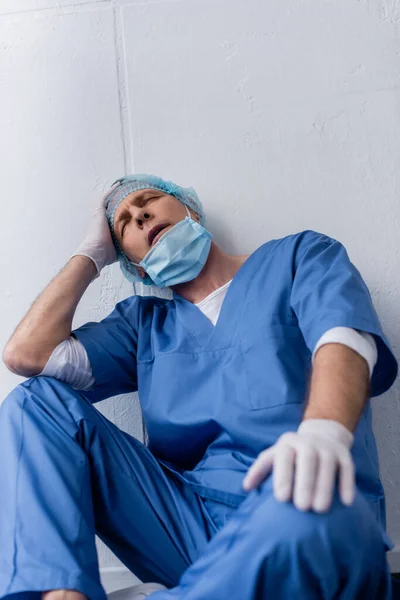 Zmęczony Dojrzały Lekarz Zamkniętymi Oczami Siedzący Przy Białej Ścianie — Zdjęcie stockowe