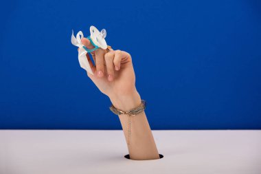 Altın bileziği olan, elinde silikon emzik tutan mavi gözlü bir kadın.
