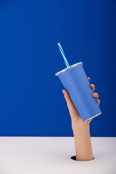 обрезанный вид женщины, держащей бумажную чашку с безалкогольным напитком изолированы на синий
