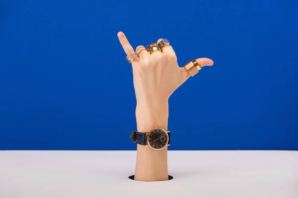 cropped view of woman with wrist watch and rings showing call me gesture isolated on blue
