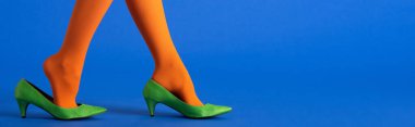 Parlak turuncu taytlı ve mavi ayakkabılı kadının panoramik görüntüsü.
