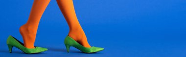 Parlak turuncu taytlı ve mavi ayakkabılı kadının panoramik görüntüsü.