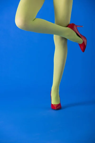 Обрезанный Вид Модели Зеленых Колготках Красных Каблуках Стоящих Синем — стоковое фото
