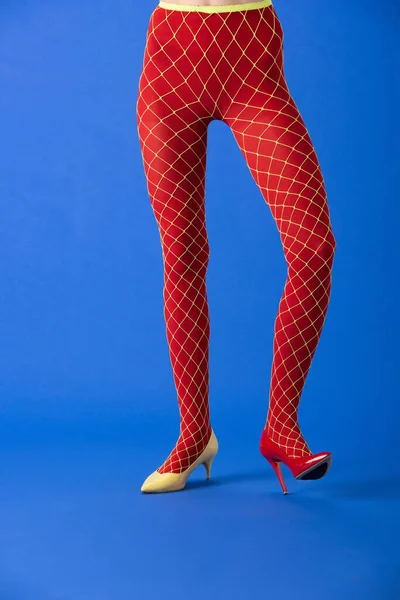 Cropped View Model Fishnet Tights Yellow Red Heels Standing Blue — Stock Photo, Image