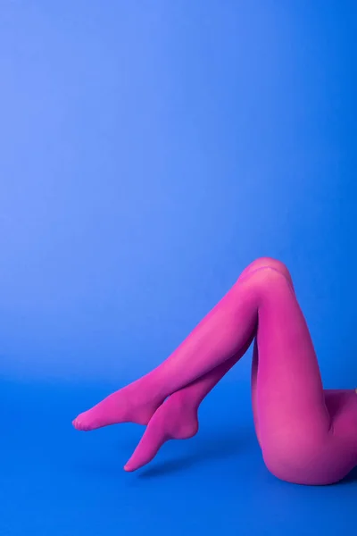青い上にポーズをとる明るい紫色のタイツ姿の女性のクロップドビュー — ストック写真