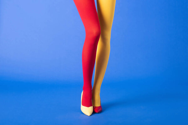 cropped view of model in yellow and red tights and shoes standing on blue