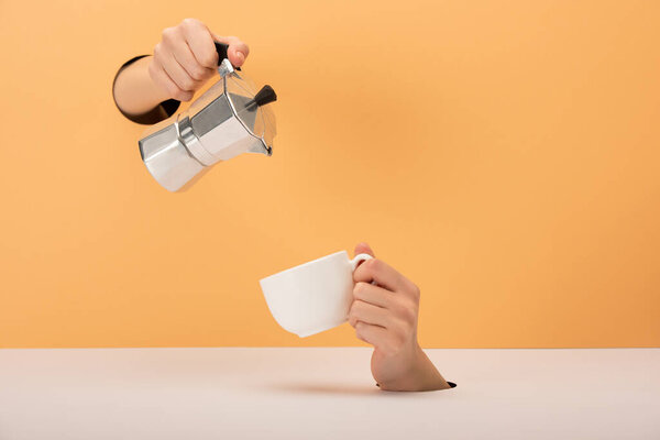 cropped view of woman holding coffee pot near cup on orange and white 