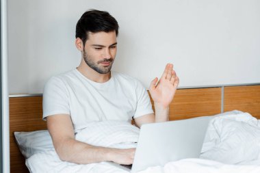 Yakışıklı bir adamın yatak odasında dizüstü bilgisayarında video araması seçici odak noktası.