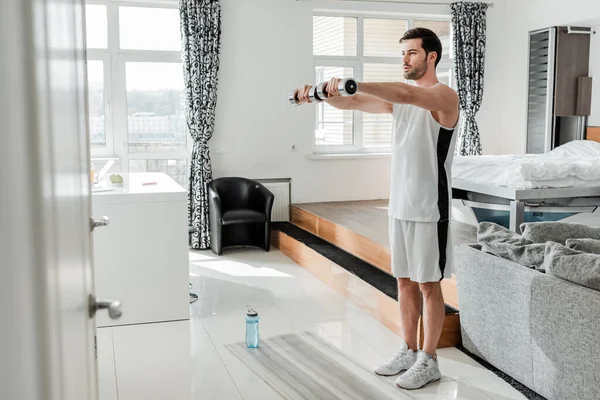 男人在家里健身垫附近与哑铃一起锻炼的选择性焦点 — 图库照片