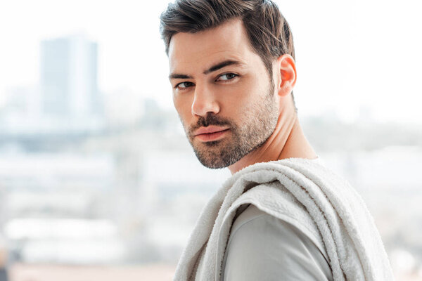 Side view of handsome man with towel on shoulder looking away at home