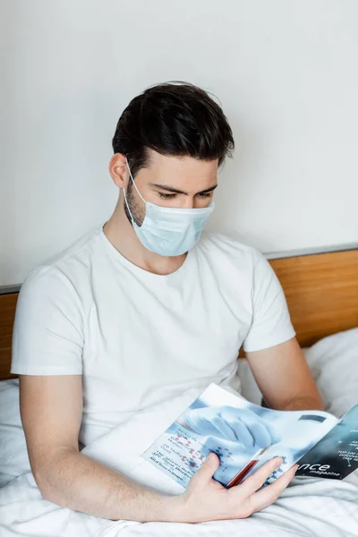 Hombre Revista Lectura Máscara Médica Cama — Foto de Stock