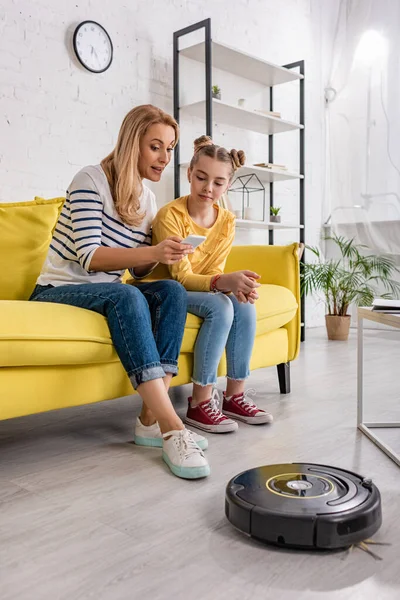 Ibu Dan Anak Melihat Smartphone Sofa Dekat Robot Vacuum Cleaner — Stok Foto