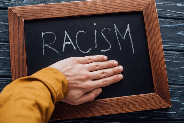 Cropped View Man Holding Hand Blackboard Racism Lettering Dark Wooden — Stock Photo, Image