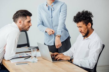 İş kadını, Afrika kökenli Amerikalı iş arkadaşının yanındaki kol saatini işaret ediyor. 