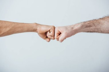 Cropped view of men doing fist bump isolated on grey  clipart