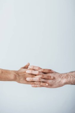 Gri yolda el ele tutuşan adamların kesikli görüntüsü.