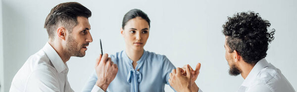 Панорамный снимок мультиэтнических бизнесменов, смотрящих на африканского американского коллегу в офисе
 