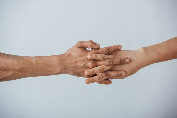 Cropped view of men holding hands isolated on grey