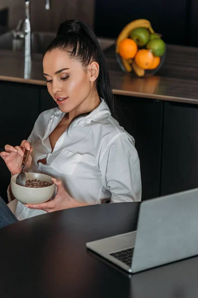 Verträumte Frau Hält Schüssel Mit Frühstück Der Nähe Von Laptop — Stockfoto