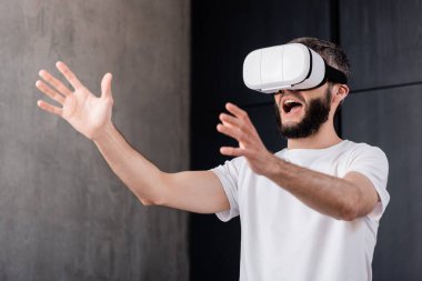 Shocked man using virtual reality headset at home 