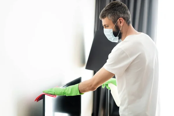 Widok Boku Człowieka Masce Medycznej Czyszczenia Szmatą Detergentem Salonie — Zdjęcie stockowe
