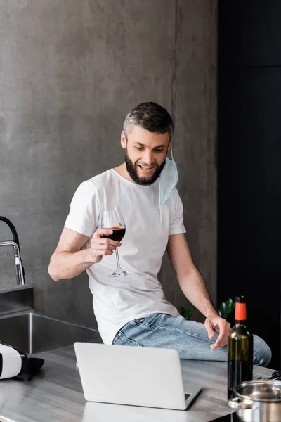 Homme Souriant Dans Masque Médical Tenant Verre Vin Près Ordinateur — Photo