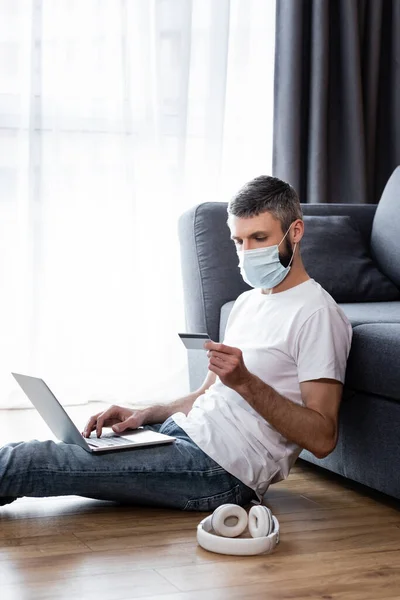 Side View Man Medical Mask Using Laptop Credit Card Headphones — Stock Photo, Image