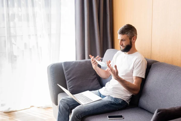 Man Holding Medical Mask Digital Devices Sofa Living Room — Stock Photo, Image