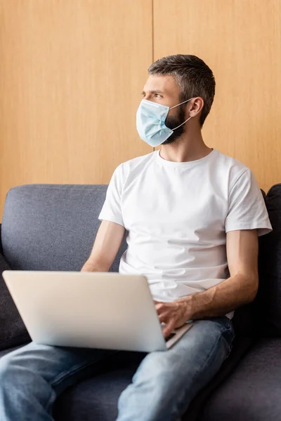 Selective Focus Teleworker Medical Mask Looking Away While Using Laptop — Stock Photo, Image