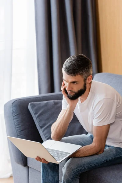 Důmyslný Telepracovník Drží Notebook Gauči Doma — Stock fotografie