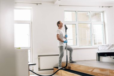 Elektrikli süpürge tutan mutlu adamın seçici odağı 