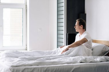 side view of man looking at window in bedroom  clipart