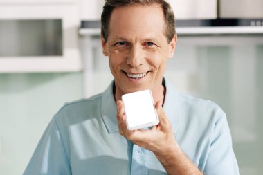 Mutlu adam sesli mesaj kaydederken beyaz ekranlı akıllı telefonu tutuyor 