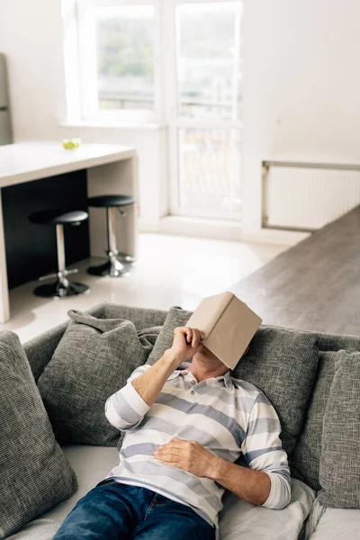 Adam Oturma Odasında Yüzünü Örterken Kanepeye Uzanıp Kitaba Dokunuyor — Stok fotoğraf