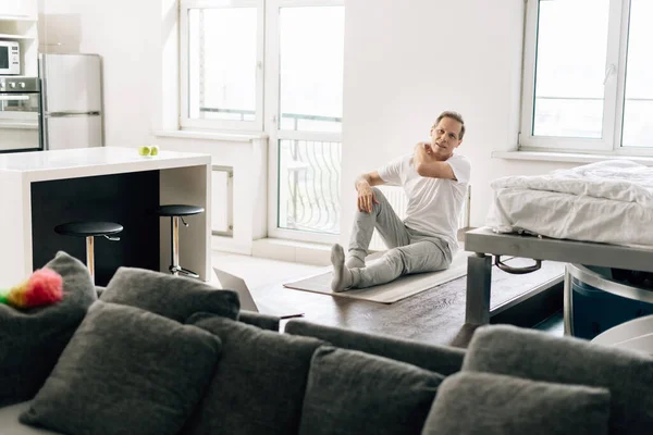 selective focus of man on fitness mat watching online exercise on laptop at home